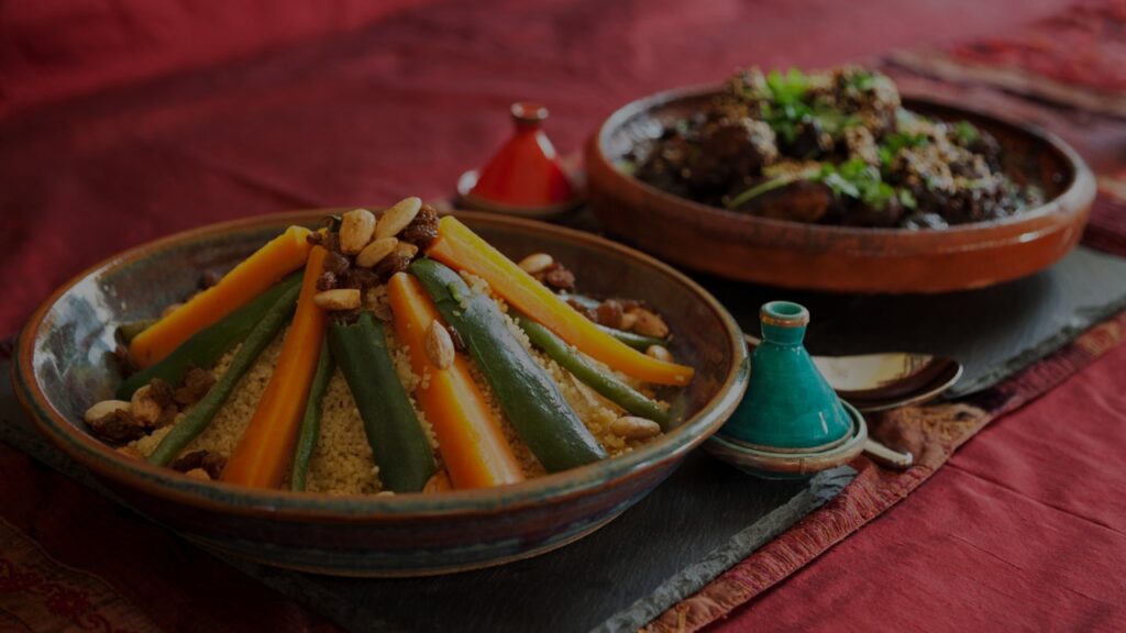 Achtsamkeit beim Mittagessen praktizieren: Zwei orientalische Tonschalen gefüllt mit Reis, Gemüse und Fleischbällchen, angerichtet auf einer dunkelrot-glänzenden Tischdecke.
